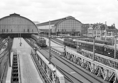 849031 Gezicht op de perrons aan de oostzijde buiten de kap van het N.S.-station Amsterdam C.S. te Amsterdam.